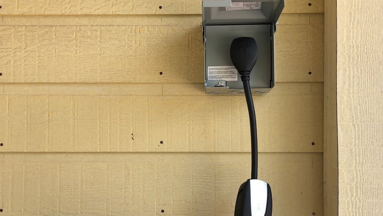 Tesla connector plugged into an outdoor weatherproof disconnect